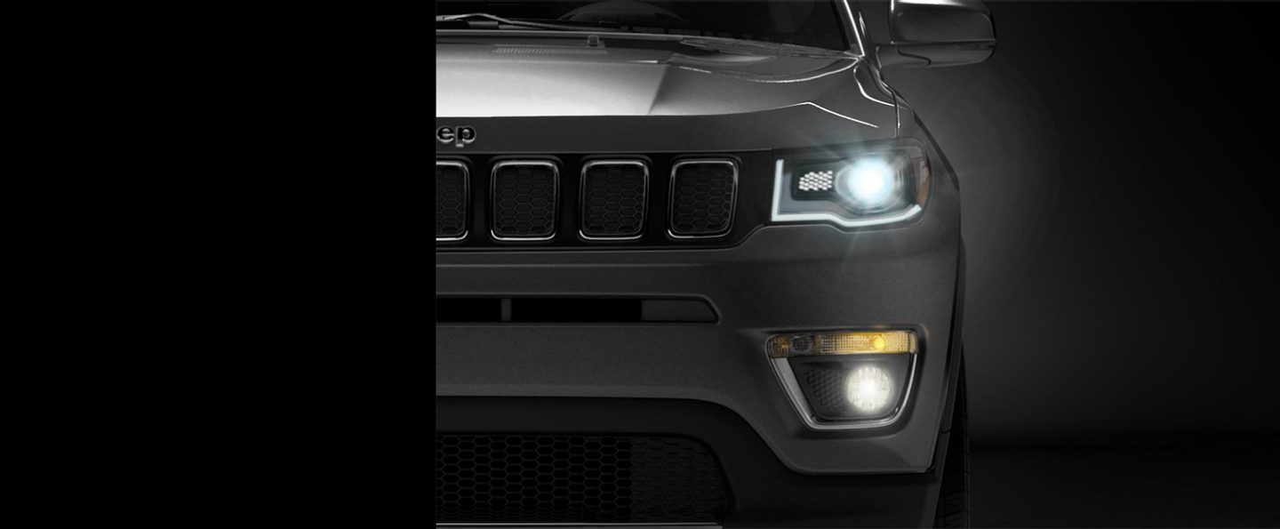The 2020 Jeep Compass with headlamps and fog lamps lit.