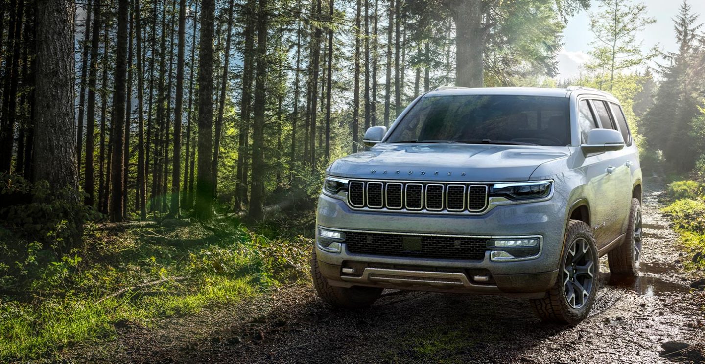 The 2022 Grand Wagoneer being driven off-road on a muddy track.