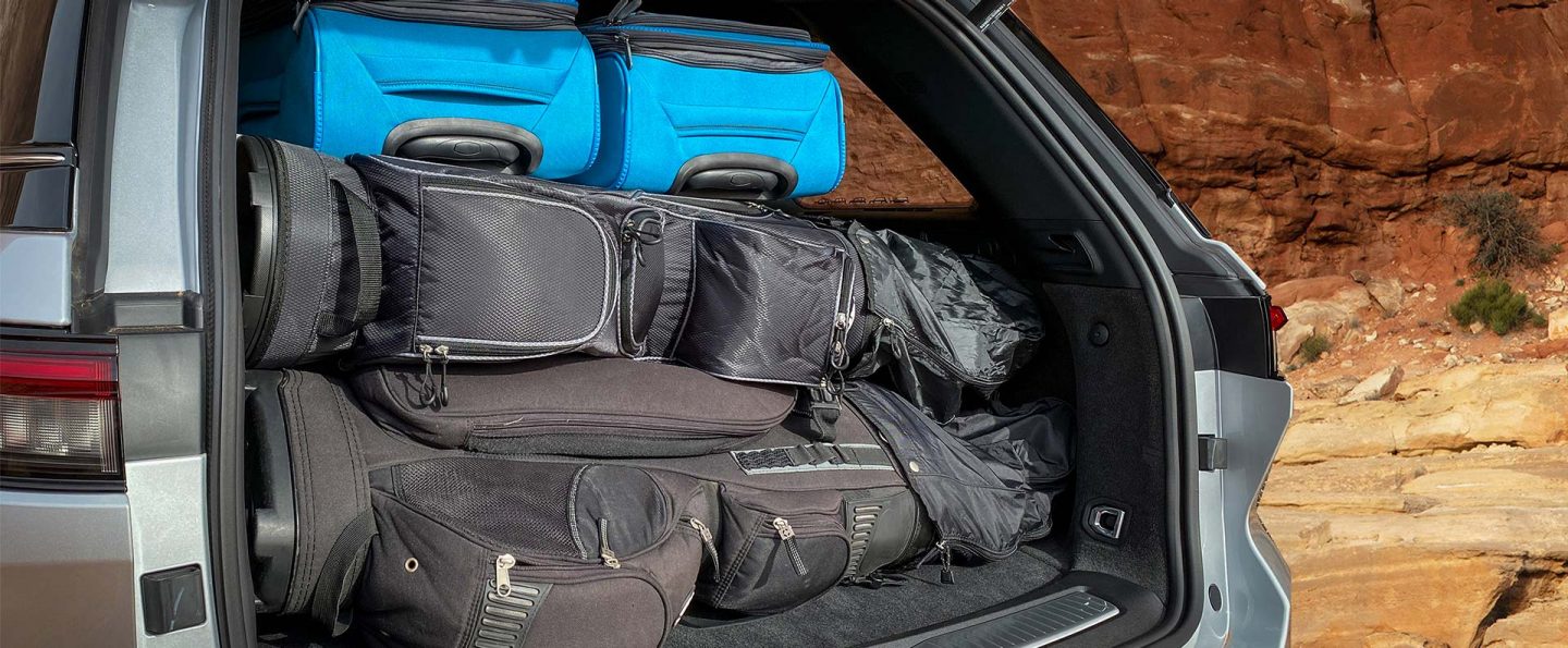 The rear cargo area of the 2023 Jeep Grand Cherokee packed with two golf bags and two suitcases.
